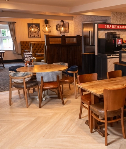 The interior restaurant seating area at The Hussey Arms in Brownhills, with upholstered booth seats and a self-serve coffee machine.