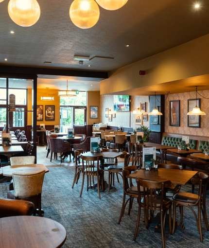 The interior restaurant seating area at The Richmond Arms, with upholstered chairs and booth seating; and framed artwork and a TV on the walls.