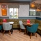 An interior restaurant seating area at the Devonshire Arms, with a large, upholstered corner seat, and framed artwork on the walls.