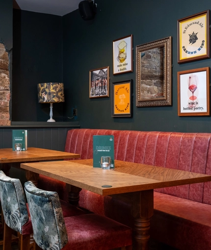 An interior restaurant seating area at the Tredegar Arms, with an upholstered booth seat, and framed artwork on the wall.