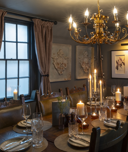 Function room with large table set up for a meal with a chandelier and a large window