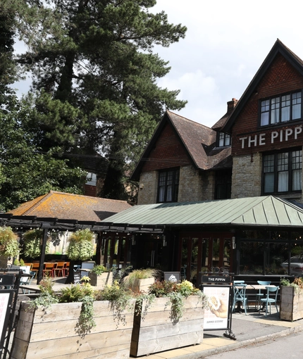 Exterior shot of the venue featuring the building and beer garden seating area and a glimpse of the car park