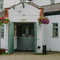The exterior facade, signboard, and entrance to The Green Man in Brackley Hatch, with flower baskets hanging on the walls. 