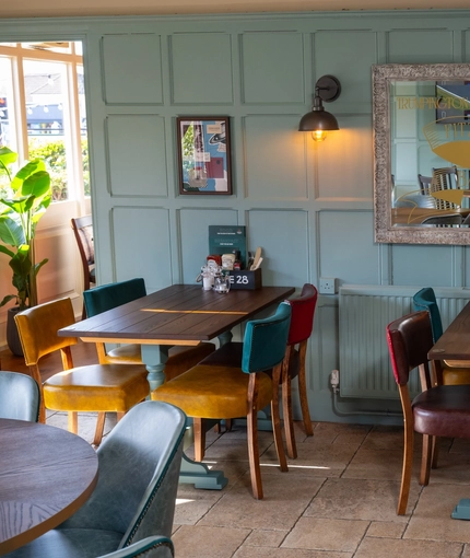 An interior restaurant seating area at the Golden Hind, with tiled flooring, wood panelled wall, and upholstered chairs.