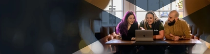 People sitting around a laptop in a seating area of a Greene King pub.