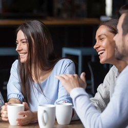 A group of people laughing while drinking coffee.
