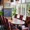 The interior restaurant seating area with tables, chairs, cushioned seating, potted plants and wall mounted TV at The Church View Inn.