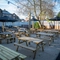 The exterior beer garden seating area at The Horsforth in Horsforth, with wooden picnic tables, shade umbrellas, and string lights overhead.