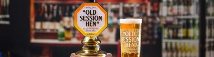 A pint of Old Session Hen next to the pump on a bar.