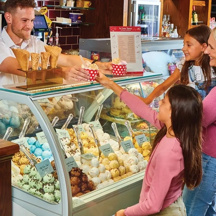mum and 2 children being served ice cream by staff member at ice cream counter