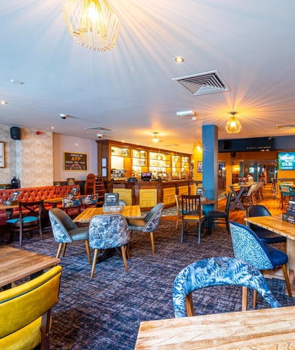The bar and interior restaurant seating area at the Counting House, with TVs on the walls, and upholstered booth seating.