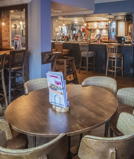 Interior dining area of a pub with a bar and a TV.