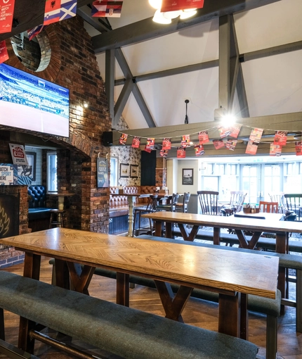 Interior dining area of a pub with a fireplace and a TV.