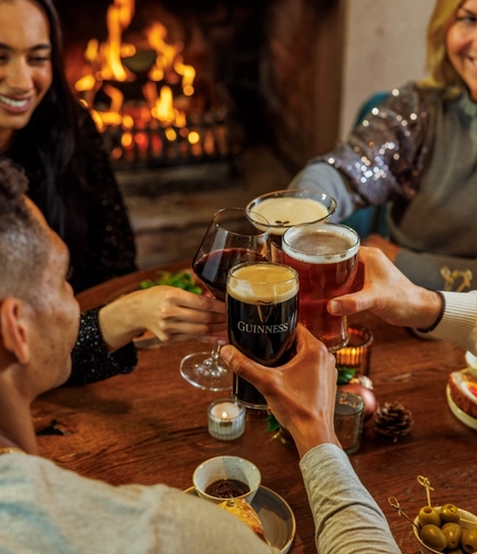 An image of people enjoying festive bar snacks and drinks within the interior restaurant seating area with fireplace at The Watermill.