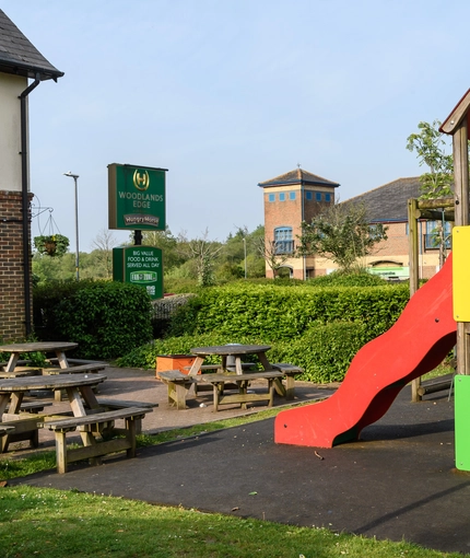 Exterior beer garden of a pub with a seating area and a playground.