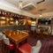 Interior dining area of a pub with a bar, a TV, a fireplace and a gambling machine.