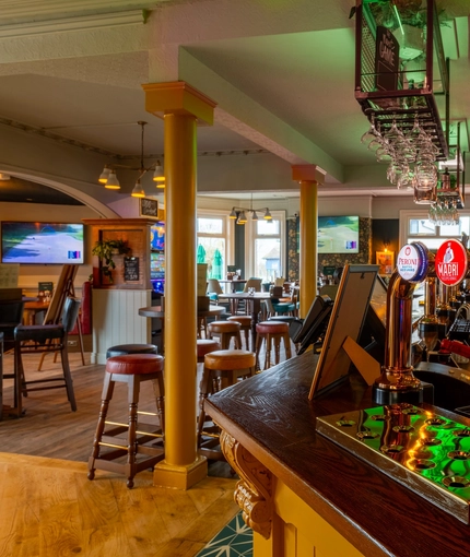 A close up view of a golden drinks tray and the beer taps for Peroni, Madri, Level Head, and Hazy Day, on the bar inside the Malvern Tavern.