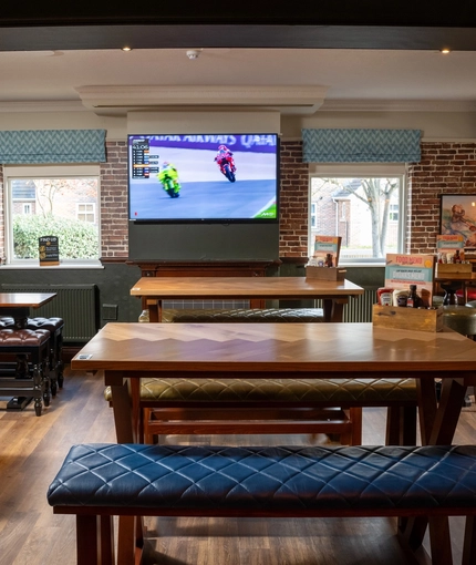 An interior restaurant seating area of The Longship, with upholstered bench seats, TVs on the walls, and a fireplace.