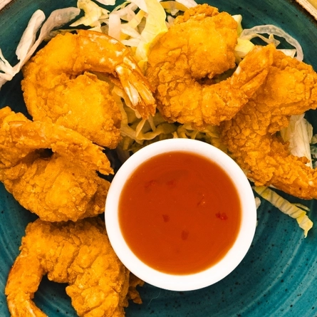 A sharer of king prawns served to advertise classics on offer at Flaming Grill venues on a textured orange background.
