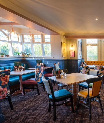 The interior restaurant seating area at The Talbot Inn in Mansfield, with booth window seats, wooden tables, and upholstered chairs.