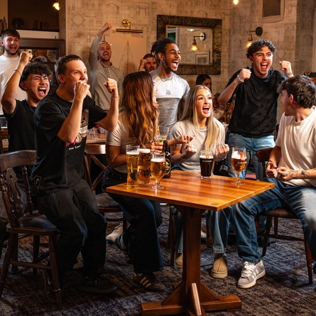 A group of friends watching and cheering at the Football.