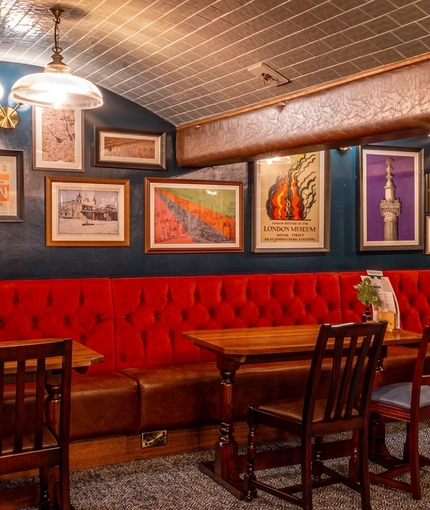 An interior restaurant seating area at the Monument, with booth seating beneath tiled arches, and framed artwork on the wall.