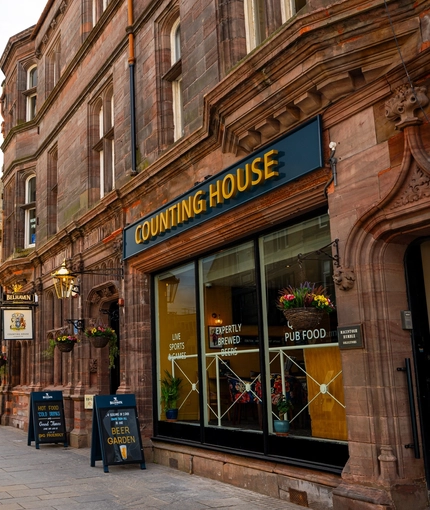 The exterior facade and signage of the Counting House, with flower baskets hanging on the walls.