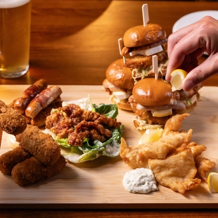 A close up lifestyle image showing hands interacting with a Christmas/Festive sharing board sat on a table within the interior restaurant seating area.