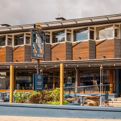 The exterior facade, signage and beer garden seating area of The Merlin in Edinburgh.