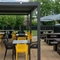 The paved exterior beer garden seating area of The Amington in Tamworth; with wooden picnic tables, shade umbrellas, string lights, and an under cover section.