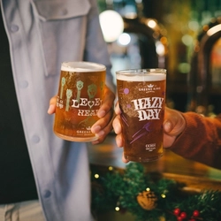 Two people inside a pub bar area, one of them holding a glass of Level Head IPA and the other holding a glass of Hazy Day IPA.