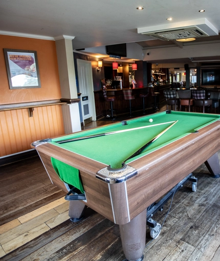 Interior dining area of a pub with a pool table.