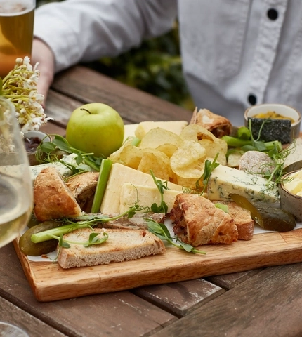 An exterior shot of people enjoying food served in a beer garden at a Chef & Brewer venue.