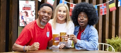 A mixed group of people, sitting at an outdoor table, reacting to a sport event.