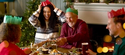 An image of 4 people sat around a table within the exterior restaurant and seating area pulling a Christmas cracker and enjoying various main dishes and drinks being poured available at Chef & Brewer venues.