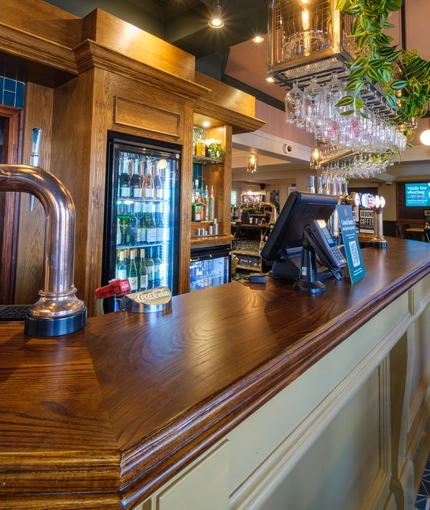 A close up view of the bar inside The Talbot Inn, with wine glasses hanging in racks above the counter.