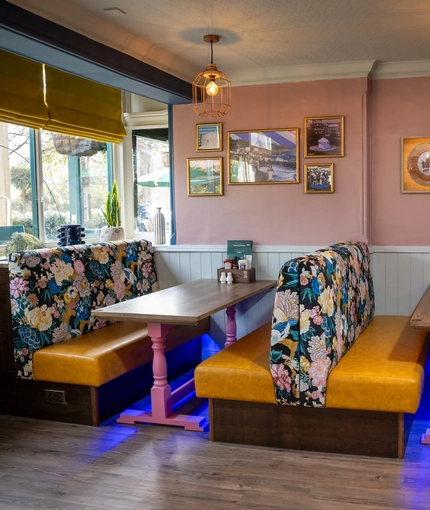 An interior restaurant seating area at The Grosvenor, with upholstered booth seats, and framed artwork on the wall.