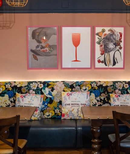 An interior restaurant seating area at The Royal Oak, with an upholstered booth seat, and framed artwork on the wall above it.
