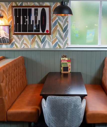 A close up view of one of the restaurant booths inside the Devonshire Arms, with upholstered seats, and framed artwork on the wall above it.