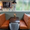 A close up view of one of the restaurant booths inside the Devonshire Arms, with upholstered seats, and framed artwork on the wall above it.