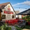 The exterior of the venue and beer garden seating area with tables, chairs, planters and string lighting at The Castle View.