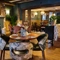 The interior restaurant seating area of the Smiths Arms pub, with fireplace, wooden beams, upholstered seats and wooden tables.