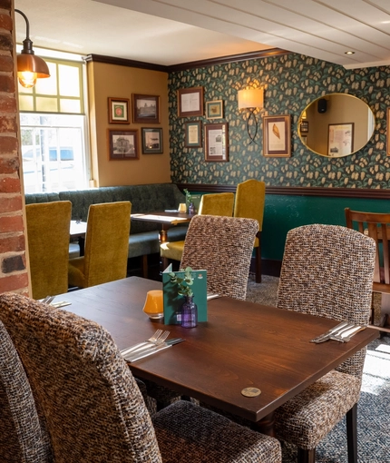 The interior restaurant seating area of The Fox, with booth seating, and framed artwork on the walls.