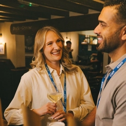 Two customers stood at the bar with a glass of white wine and a pint of Level Head in a Greene King venue.