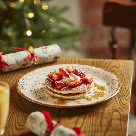 A 715x715 advertising Merry Mornings image featuring pancakes and fruit available at Chef & Brewer venues.