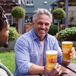 Two people sat in a beer garden enjoying a pint of Hazy Day.
