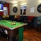 Interior dining area of a pub with a pool table, a TV and a few dartboards.