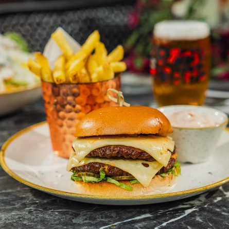 A plated Rib Burger with chips dish sat on a table within the exterior beer garden seating area at a Crafted venue.