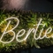 A neon sign on the wall that says 'Berties'.