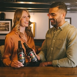 Two friends stood at the bar drinking alcohol free Kopparberg in a Greene King venue.